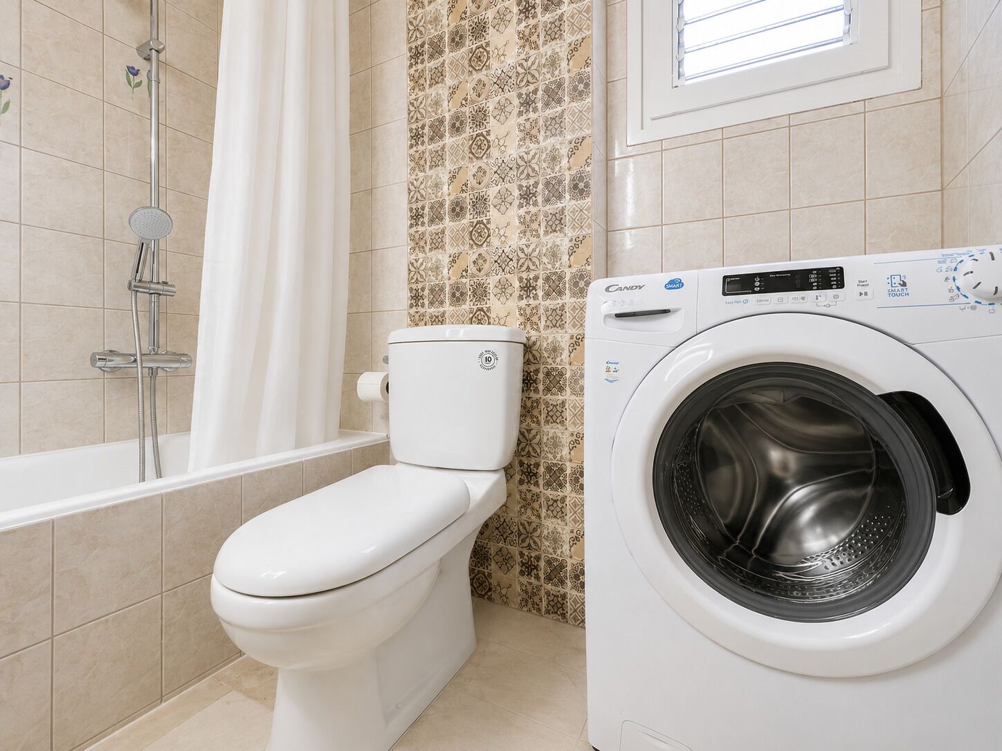 A bathroom with a toilet, a shower, and a front-loading washing machine.