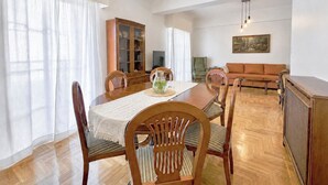 A dining area with a wooden table, chairs, a cabinet, and a television. - Acropolis Panorama 2BRM Apartment by MΡS (Athina)