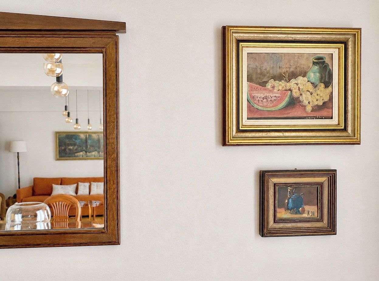 A room with a large mirror, two framed artworks, and a sofa.