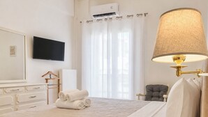 A hotel room with a bed, a TV, a lamp, a chair, and a window with curtains. - Acropolis Panorama 2BRM Apartment by MΡS (Athina)