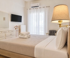 Ein Hotelzimmer mit Bett, Fernseher, Lampe, Stuhl und einem Fenster mit Vorhängen.