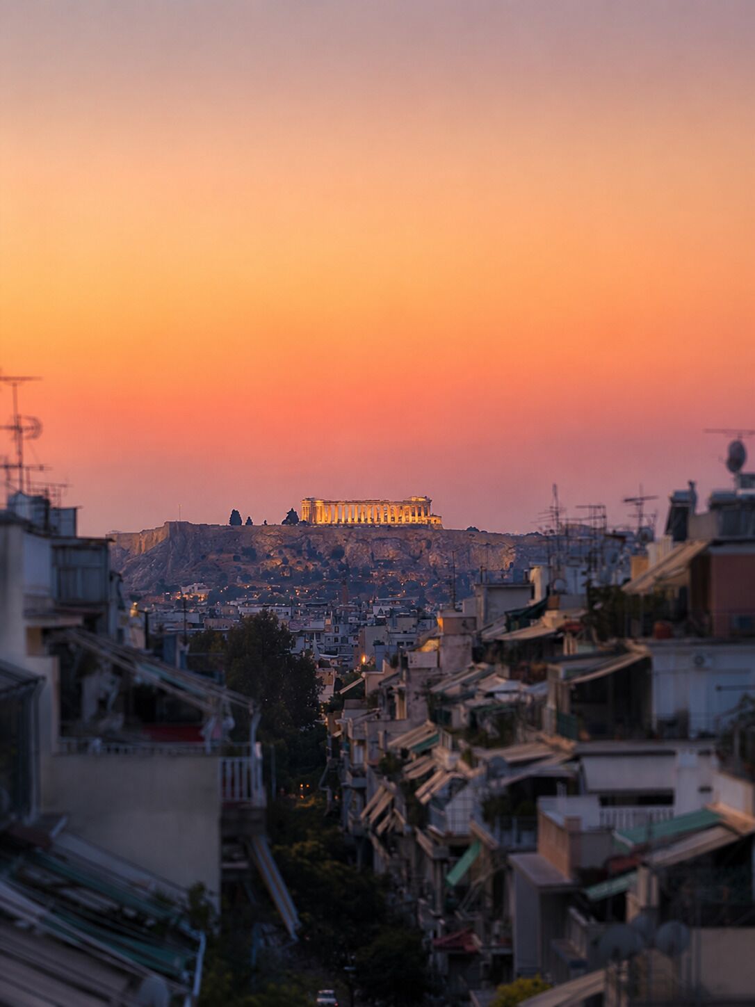 A cityscape with a prominent ancient structure on a hill, surrounded by residential buildings.