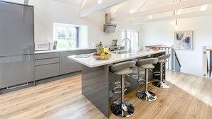 Uma cozinha moderna com uma ilha grande, banquetas e vista para o exterior.