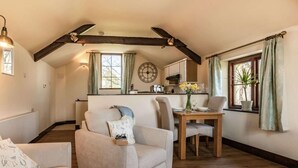 Ein gemütliches Interieur mit Essbereich, einer Couch und einer Küche im Hintergrund.