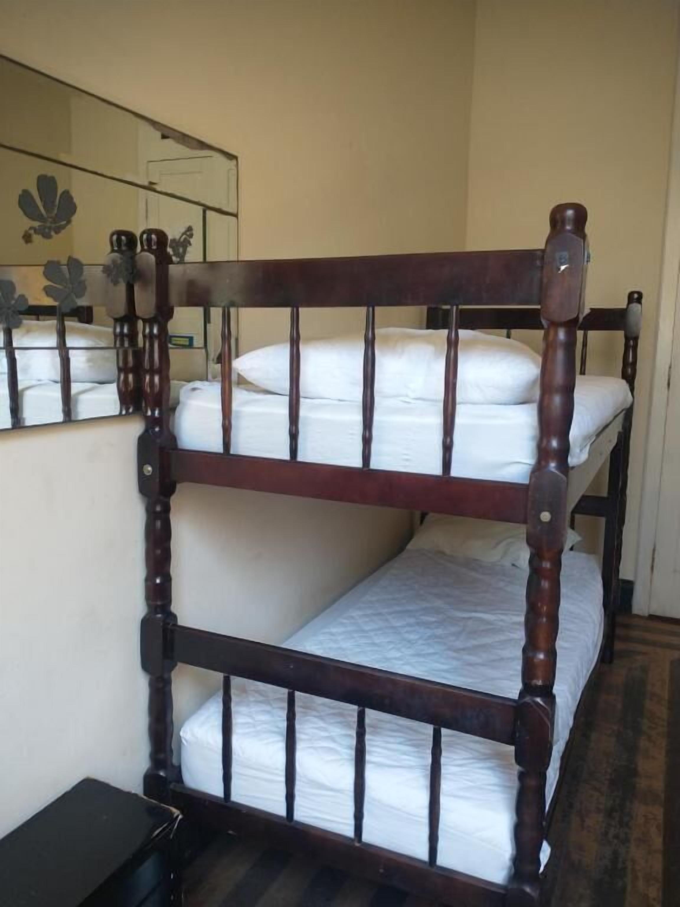 Un letto a castello con struttura in legno e biancheria bianca.