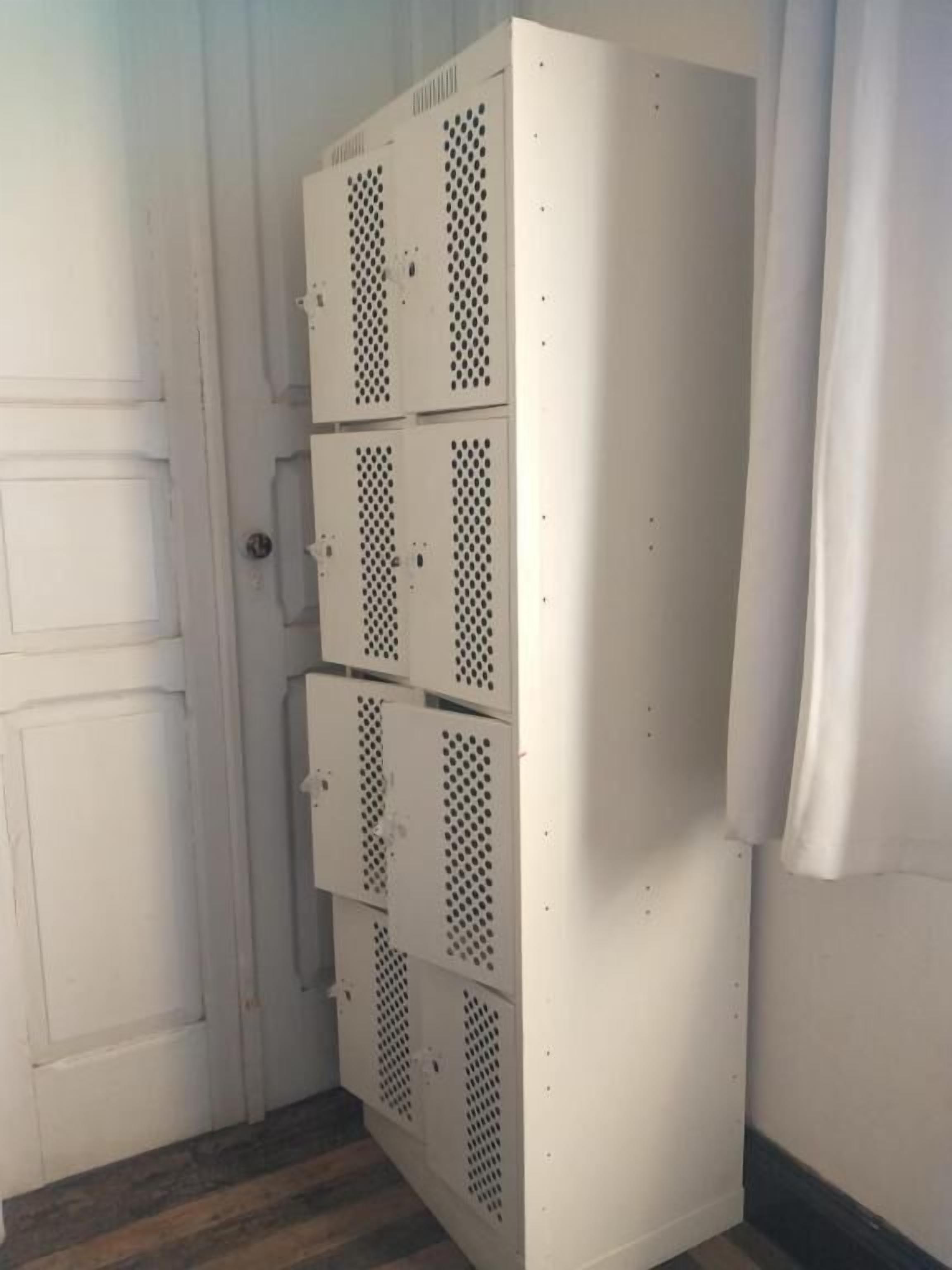 Un armario metálico blanco con varios compartimentos, una puerta y una cortina.