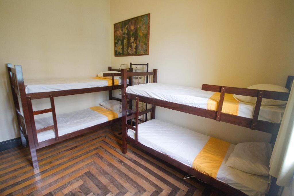 Una habitación con tres literas, piso de madera y un cuadro en la pared.