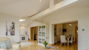 A spacious living area with a sofa, coffee table, and a dining area with chairs and a table. - 3 Bed in Colwyn Bay (oc-85763) (Hen Golwyn)