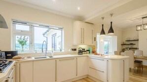 A modern kitchen with white cabinetry, a built-in stove, and a large window. - 3 Bed in Colwyn Bay (oc-85763) (Hen Golwyn)