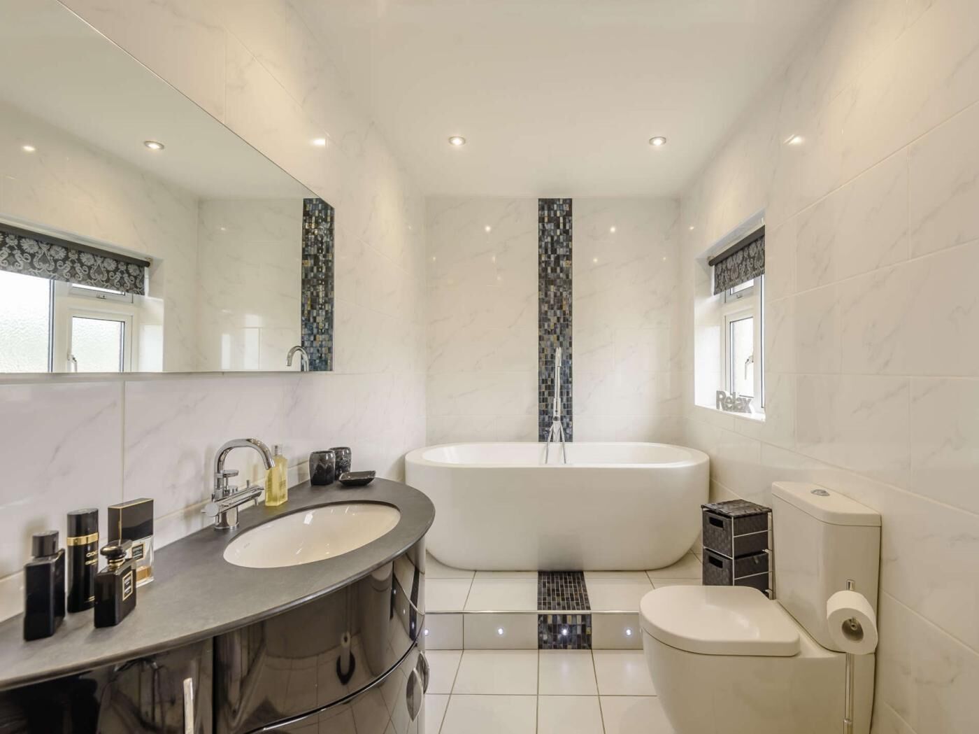 Un baño moderno con una bañera grande, un tocador con espejo y un inodoro.