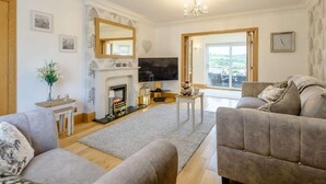 A living room with a fireplace, a television, and a sofa. - 3 Bed in Colwyn Bay (oc-85763) (Hen Golwyn)