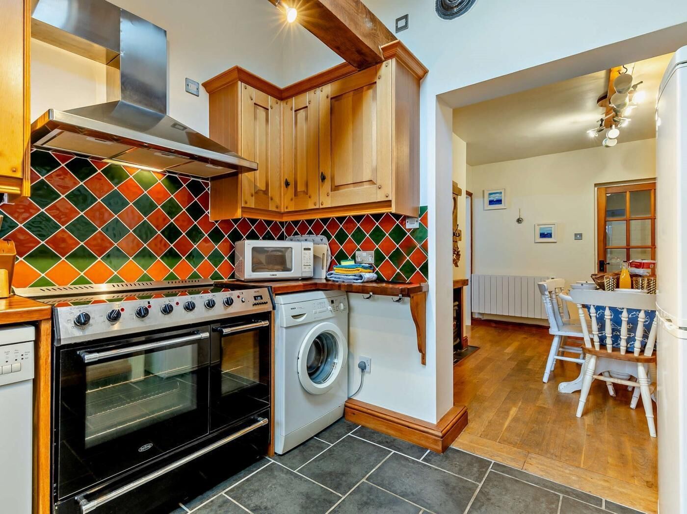 A compact kitchen with a stove, oven, microwave, and washing machine.