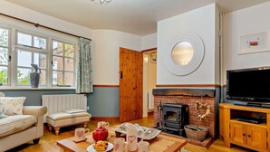 Ein gemütliches Wohnzimmer mit Kamin, Fernseher und einem Esstisch mit Teetassen und Teekanne.