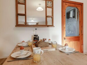 Een ontbijt met een houten tafel, een koffiezetapparaat, brood, eieren en sapglazen.