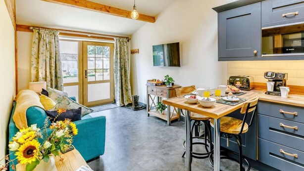 A modern kitchen with a Bosch refrigerator, a dining table with chairs, and a sofa with a floral cushion. - 1 Bed in Ripon (oc-85511) (Masham)