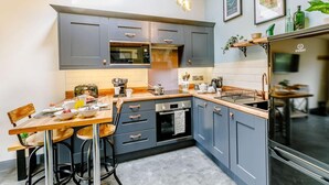 A modern kitchen with grey cabinets, a wooden dining table, and a built-in oven. - 1 Bed in Ripon (oc-85511) (Masham)