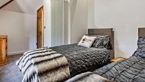 Ein Schlafzimmer mit zwei Betten, einem Holzschrank, einem Heizkörper und einer schrägen Decke.