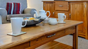 Ein Holztisch mit Teekanne, Tassen und einer Tablett mit Teebeuteln.