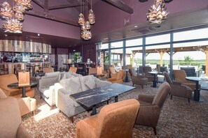 A bar area with seating, a bar counter, and a view of the outdoors.