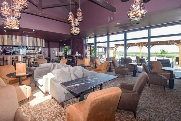 A bar area with seating, a bar counter, and a view of the outdoors.