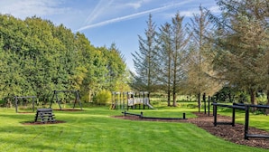 Ein Park mit einem Spielplatz, Rasenflächen und Bäumen.