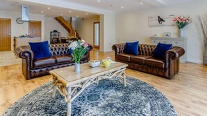 Un salon spacieux avec deux canapés en cuir, une table basse en bois et un tapis à motifs.