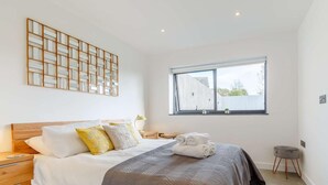 Una camera da letto con un letto, comodini, una finestra e un elemento decorativo a parete.