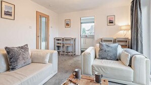 Ein modernes Wohnzimmer mit zwei Sofas, einem Couchtisch und einem Essbereich mit Stühlen.