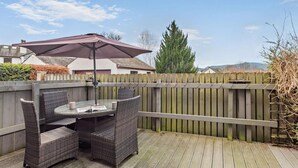 Eine Holzterrasse mit Tisch und Stühlen, einer Pergola und einem Holzzaun.