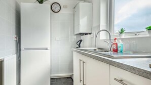 Eine moderne Küche mit weißen Schränken, einem eingebauten Backofen, einer Edelstahl-Spüle und einem Fenster mit Aussicht.