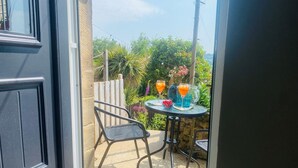 Eine Terrasse mit Tisch und Stühlen, ein kleiner Garten und Blick auf die Umgebung.