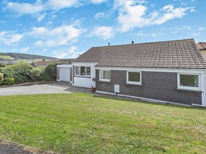 A residential property with a paved driveway, a garage, and a well-maintained lawn. - 3 Bed in Braunton (oc-86078) (Croyde)
