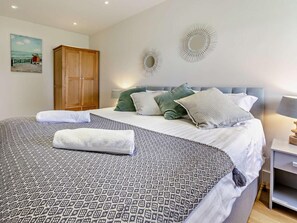 A neatly made bed with patterned bedding, a wooden wardrobe, and two wall-mounted decorative mirrors. - 3 Bed in Braunton (oc-86078) (Croyde)