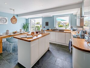 A modern kitchen with a central island, white cabinetry, and a view to the outside. - 3 Bed in Braunton (oc-86078) (Croyde)