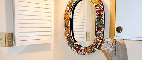 A bathroom with a granite countertop sink, a mirror with a decorative frame, and a towel hanging on the wall.