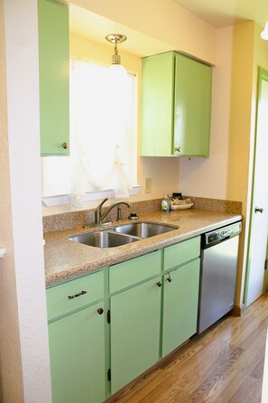 A kitchen with green cabinets, a stainless steel sink, and a dishwasher. - Rockport Racquet and Yacht Club - 68 (Rockport)