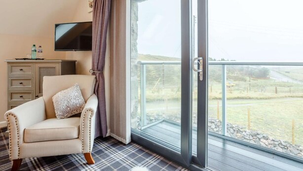 A room with a sofa, a flat-screen TV, a dresser, and a sliding glass door leading to an outdoor area.