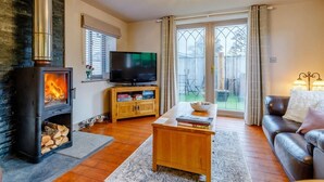 Un salon avec une cheminée, un téléviseur, un canapé et une table à manger.