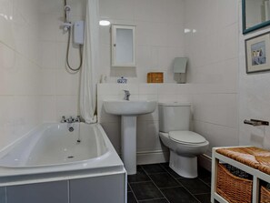 Ein Badezimmer mit Badewanne, Waschbecken, Toilette und einem Korbwannenmöbel.