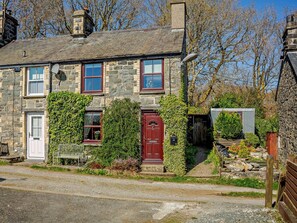 A stone house with a red door, a white door, and a window with a white frame. - 2 Bed in Blaenau Ffestiniog (oc-86064) (Gellilydan)