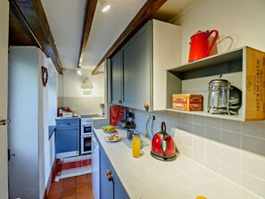 Eine Küche mit einem blauen Schrank, einem roten Wasserkocher und einem Regal mit Küchenutensilien.
