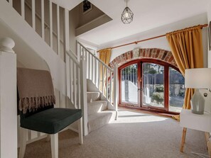 Eine Treppe mit Sitzbank, einer Lampe und Blick durch eine Glastür mit Vorhängen.