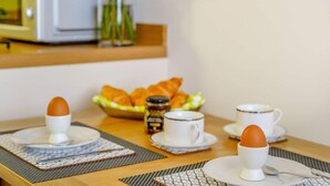 En morgenmadsopsætning med æg, croissanter og kaffekopper på et bord.