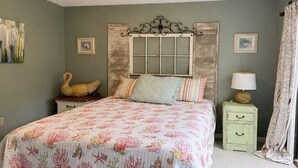 A bedroom with a bed, a nightstand, a lamp, and a decorative swan. - Wight Tide Landing (Midway)