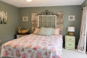 A bedroom with a bed, a nightstand, a lamp, and a decorative swan. - Wight Tide Landing (Midway)