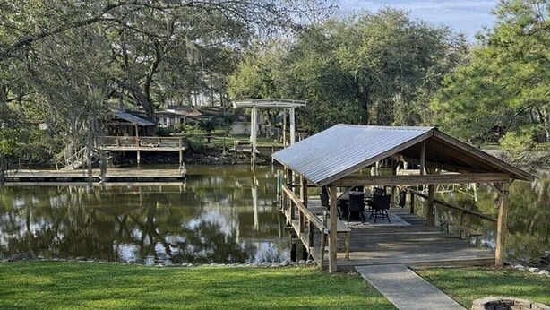 A wooden dock extending over a calm lake, a gazebo, and a small building with a deck. - Wight Tide Landing (Midway)