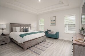 A bedroom with a wooden bed, bedside tables, a sofa, and a large window with blinds. - Close to Vilano Beach - Private Hot Tub (St. Augustine)