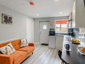 Une cuisine moderne avec un coin repas, un canapé et une horloge au mur.