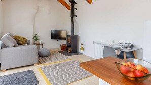 Uma sala de estar aconchegante com sofá, televisão, lareira e um espaço de jantar com mesa e cadeiras.