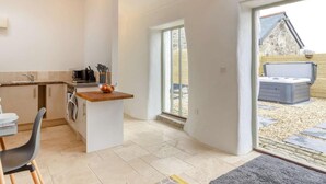 Uma cozinha moderna com uma ilha central, uma área de refeições com mesa e cadeiras, e uma grande porta de vidro deslizante que dá para um pátio externo.